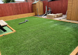 Backyard with artificial grass, wooden sheds, and a small structure.