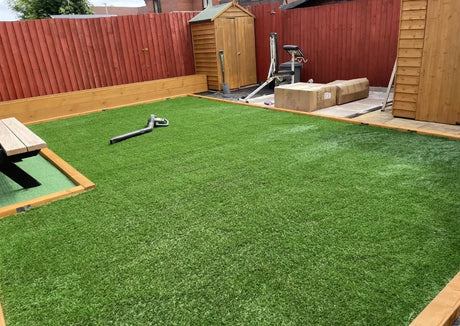 Backyard with artificial grass, wooden sheds, and a small structure.