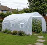 4.5 x 3 metre white polytunnel greenhouse set up in a UK back garden with flower borders and stepping stones