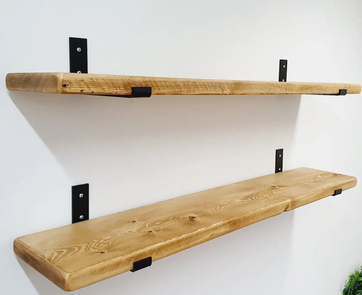Two rustic wooden floating shelves with black metal brackets mounted on a plain white wall.